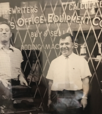 entrepreneurship | Hemophilia News Today | A sepia photo of Jennifer's grandfather smiling as he stands in front of his office equipment store in Chicago in 1951.