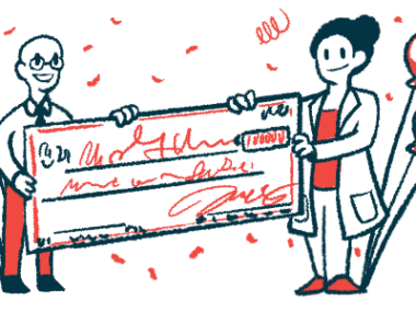 A researcher stands beside a giant check being presented to her.