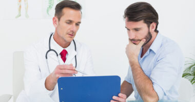 A male patient speaking with a doctor and looking at a chart.