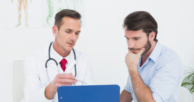 A male patient speaking with a doctor and looking at a chart.