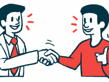 Two people smile while shaking hands.
