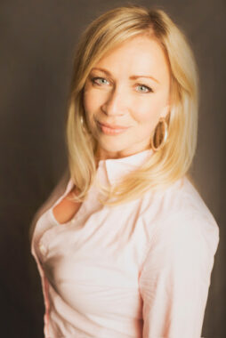 A professional headshot of a woman against a gray background.