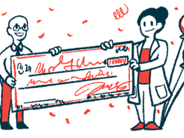 Two scientists each hold one end of a giant check amid balloons and confetti.