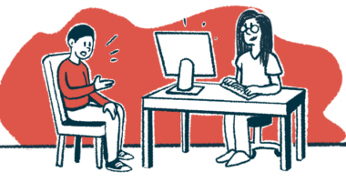 A patient talks to a doctor who is sitting at a desk in front of a computer.