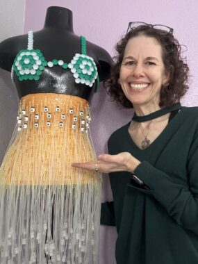 A woman poses next to the top and skirt she fashioned from medical waste.